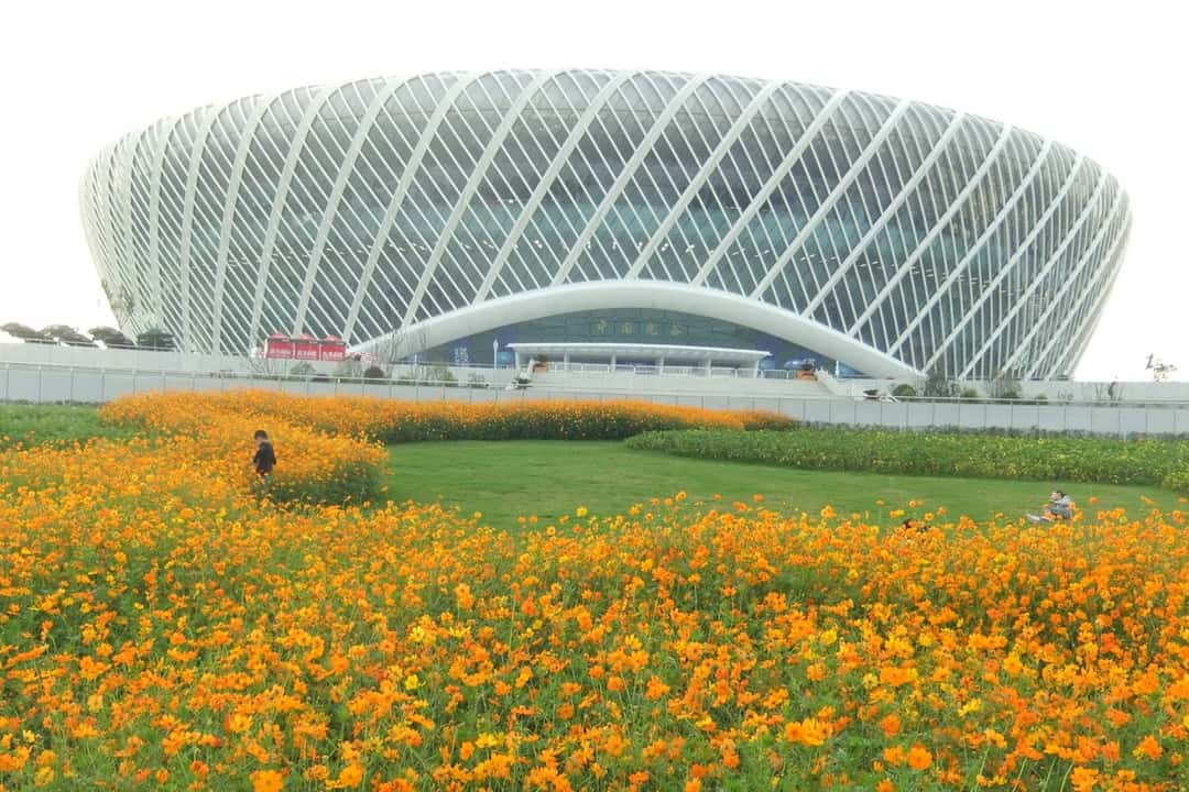 Foto de archivo: el estadio central del Optics Valley International Tennis Centre de Wuhan, con su estructura blanca de vigas cruzadas, detrás de un cantero de flores naranjas