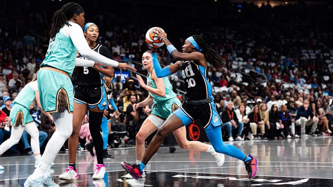 Rhyne Howard, con la camiseta negra número 10 del Atlanta Dream, ataca el aro entre jugadoras de New York Liberty mientras Angel Reese, con el número 5, sigue la jugada