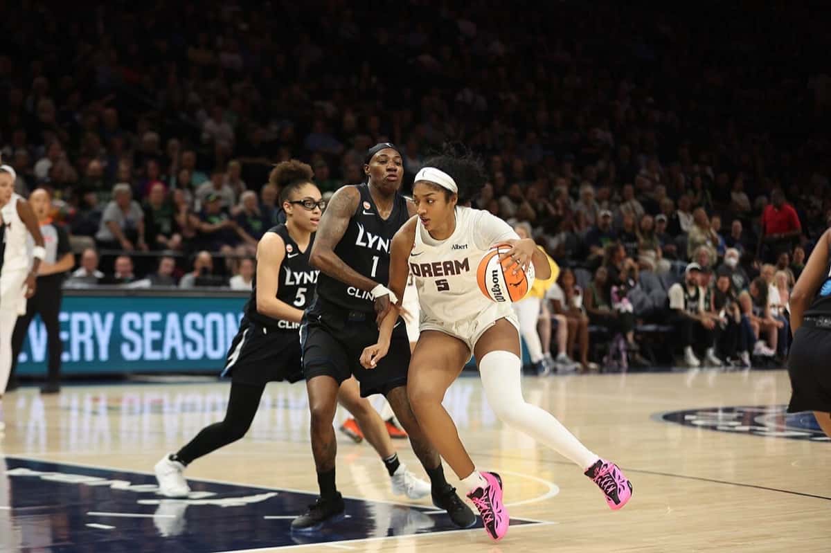 Foto de archivo: Angel Reese, con la camiseta blanca número 5 del Dream, avanza con la pelota ante dos jugadoras de las Lynx