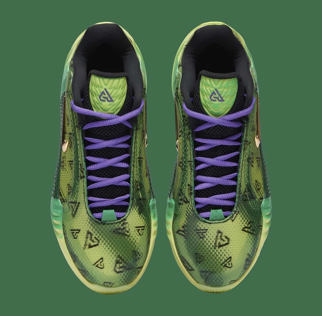 Vista superior de un par de Nike Giannis Freak 8 «Halloween» sobre fondo verde, con los cordones violetas cruzados, el interior negro, la lengüeta verde con el logo GA en violeta y los monogramas GA estampados en la puntera