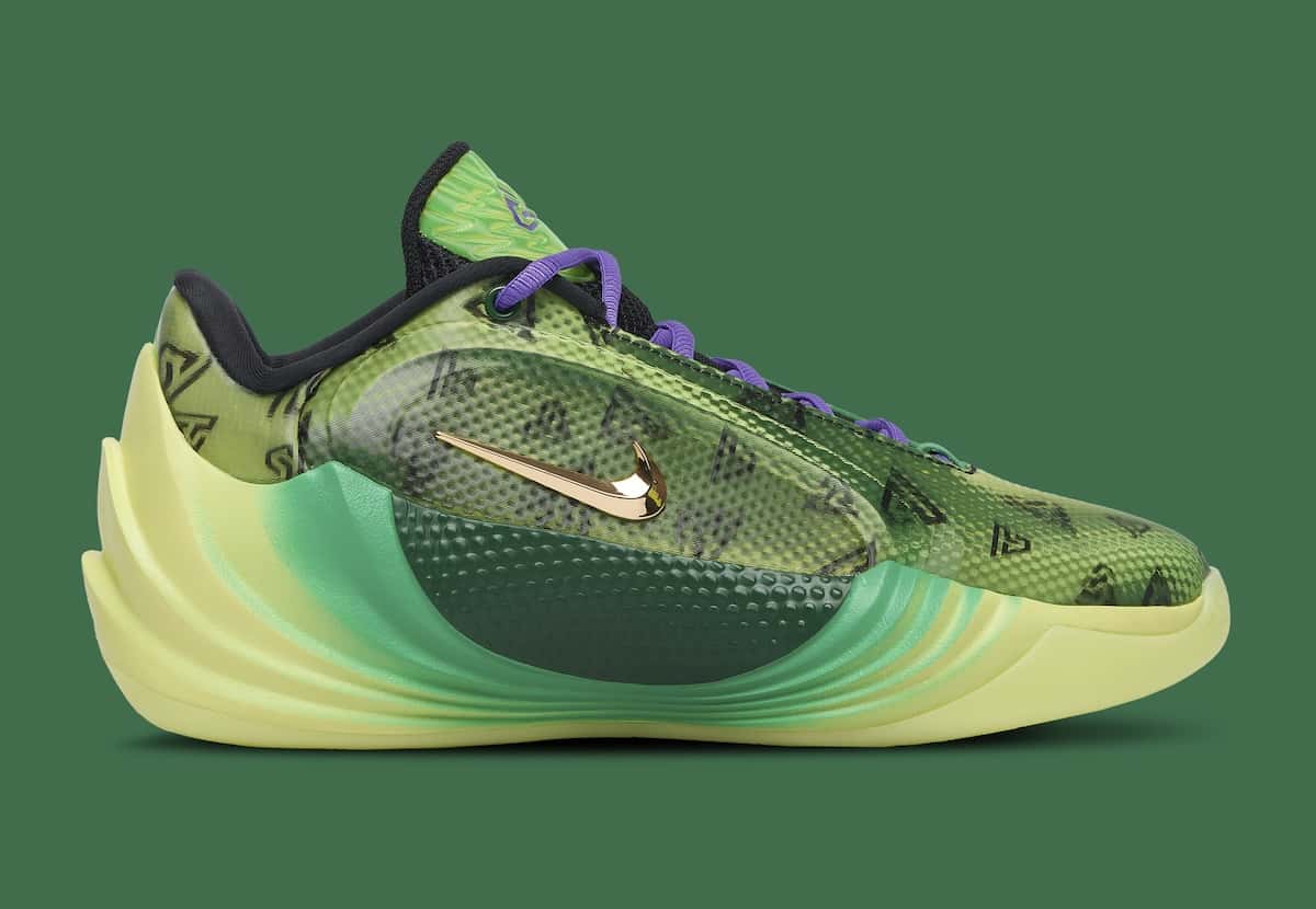 Nike Giannis Freak 8 «Halloween» de perfil lateral sobre fondo verde oscuro, con capellada verde translúcida estampada con monogramas GA negros, cordones violetas, Swoosh dorado espejado y mediasuela esculpida en degradé de verde a amarillo pálido