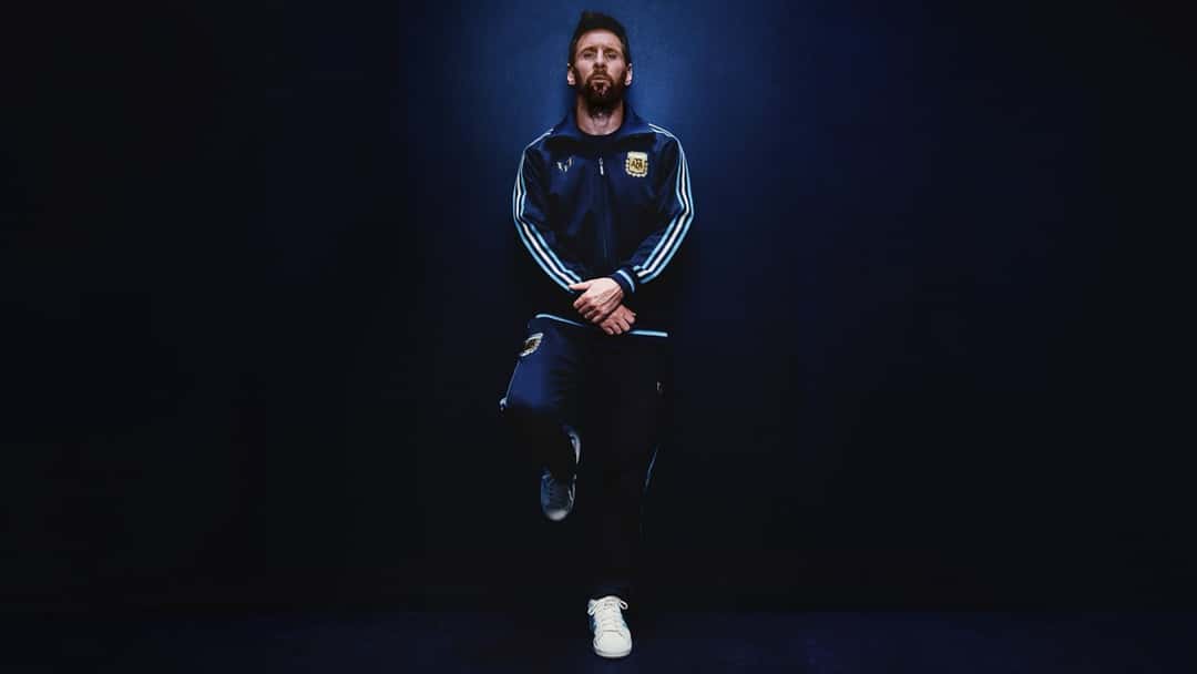 Lionel Messi con la campera y el pantalón azul marino de la línea urbana de la colección, con el escudo de la AFA y su emblema personal en el pecho (foto oficial de adidas)