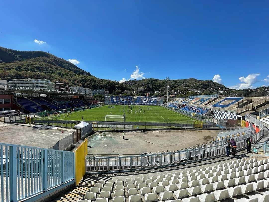 Las tribunas y el campo de juego del estadio Giuseppe Sinigaglia de Como, con los cerros de fondo y el cielo azul; foto de archivo de septiembre de 2022 (foto: Vale93b, Wikimedia Commons, licencia CC BY-SA 4.0)
