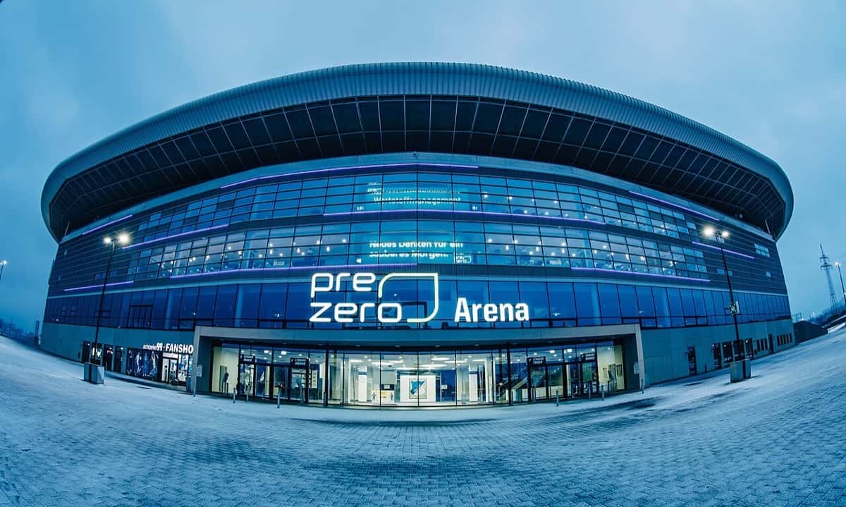 El estadio del Hoffenheim en Sinsheim, iluminado de azul al anochecer, con el cartel de la PreZero Arena sobre la entrada; foto de archivo de enero de 2019 (foto: Simon Hofmann, Wikimedia Commons, licencia CC BY-SA 4.0)