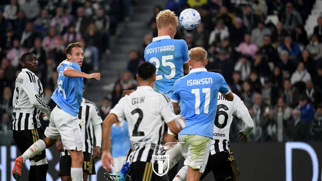 Oliver Provstgaard, de la Lazio, con la camiseta celeste y el número 25, salta a cabecear dentro del área de la Juventus, junto a Gustav Isaksen, con el 11, y defensores de la Juve de blanco y negro (foto: prensa S.S. Lazio)