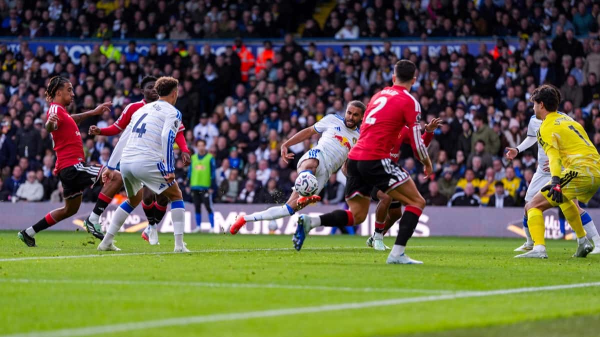 Dominic Calvert-Lewin, con la camiseta blanca de Leeds United, remata en el área de Manchester United ante la marca de jugadores de rojo y el arquero Senne Lammens en Elland Road (foto: prensa Leeds United)