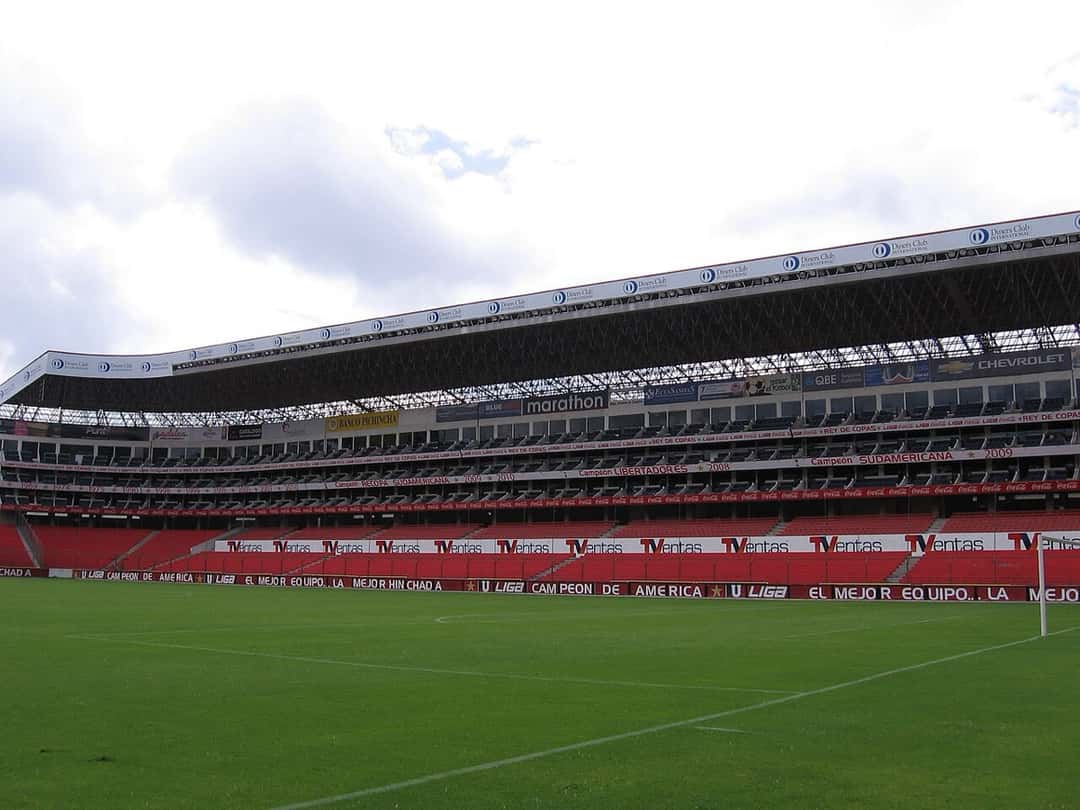 El estadio Rodrigo Paz Delgado, de Liga de Quito, con su tribuna techada de dos bandejas y las butacas rojas detrás de la cancha; foto de archivo de julio de 2011 (foto: Paulce1527, Wikimedia Commons, licencia CC BY-SA 3.0)