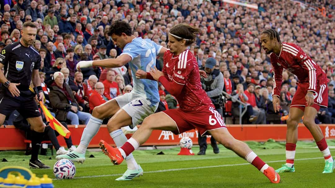 Matheus Nunes, con la camiseta celeste del Manchester City, protege la pelota contra la línea ante Milos Kerkez, de rojo, en Anfield (foto: Liverpool FC)