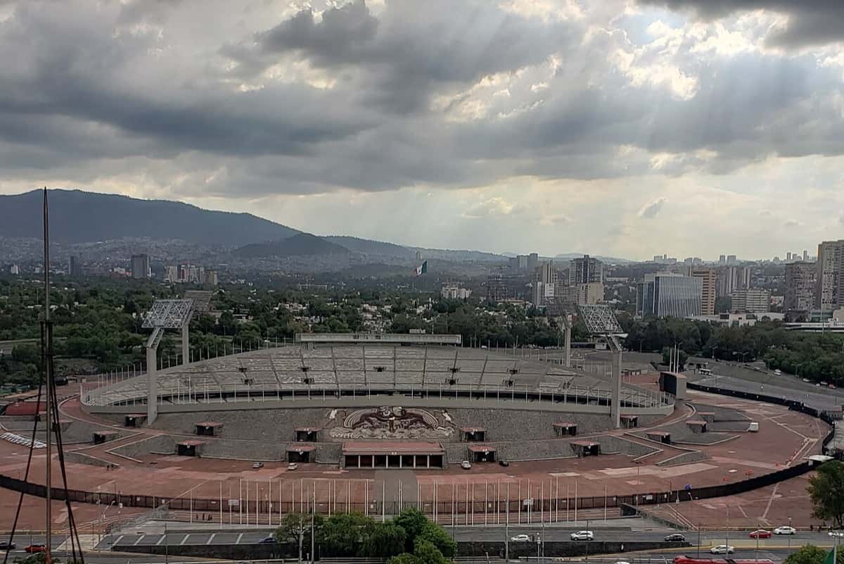 El estadio Olímpico Universitario, en la Ciudad Universitaria de la UNAM, visto desde lo alto con las montañas y la Ciudad de México de fondo; foto de archivo de 2019 (foto: Lepog, Wikimedia Commons, licencia CC BY-SA 4.0)