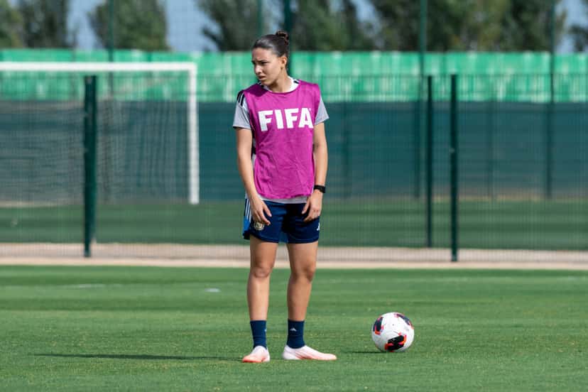 Una jugadora de la Selección argentina femenina Sub-17, con pechera rosa de entrenamiento, espera con la pelota en el piso durante la práctica del jueves 22 en una de las canchas del Complejo Mohammed VI (foto: prensa AFA)