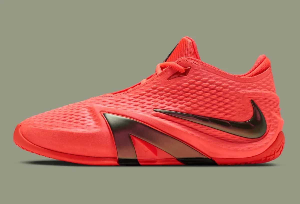 Nike Ja 4 Code Red de perfil, toda en rojo coral con el Swoosh invertido oscuro y la suela roja, sobre fondo verde grisáceo