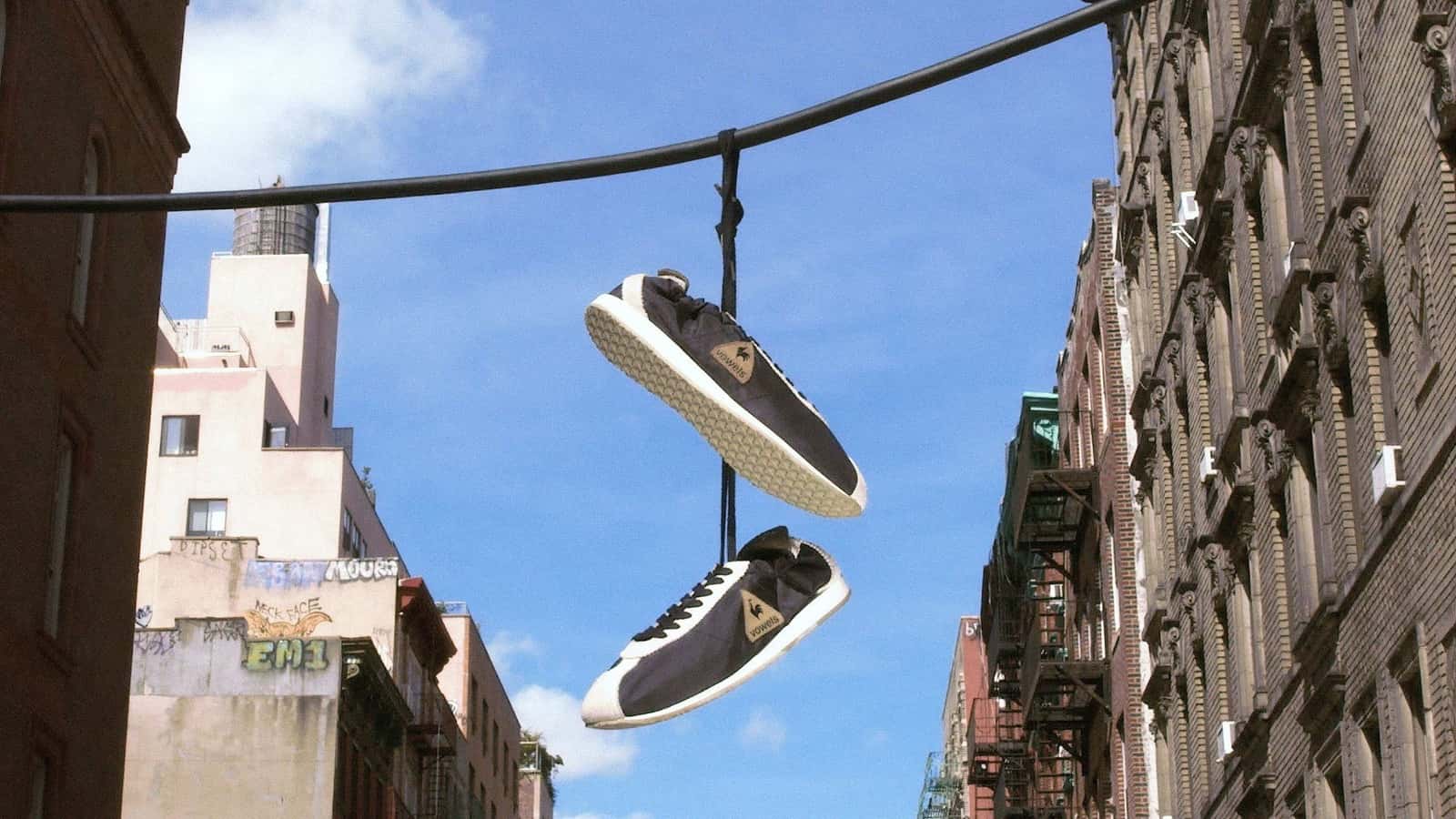 Par de vowels x Le Coq Sportif Wendon negras colgadas de un cable sobre una calle de Nueva York