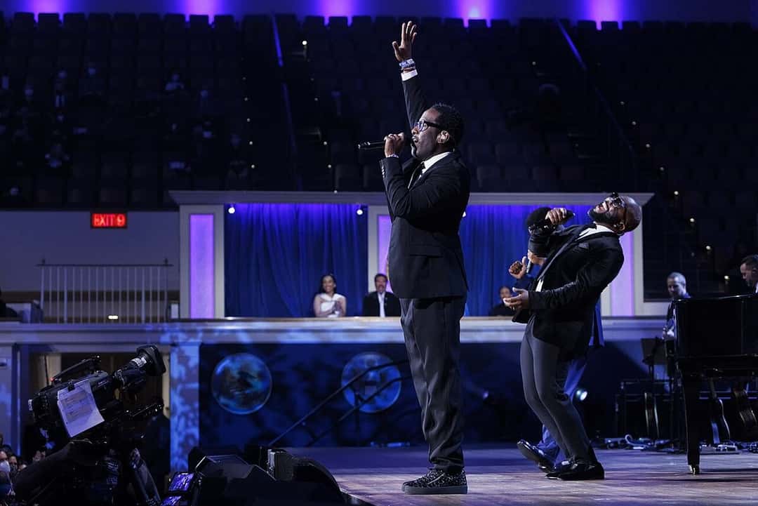 Boyz II Men cantan sobre un escenario con luces azules: uno levanta el brazo con el micrófono en la mano y otro se inclina hacia atrás, en el DAR Constitution Hall de Washington en marzo de 2022 (foto de archivo). Foto: Shawn Miller, Biblioteca del Congreso de Estados Unidos, dominio público, vía Wikimedia Commons