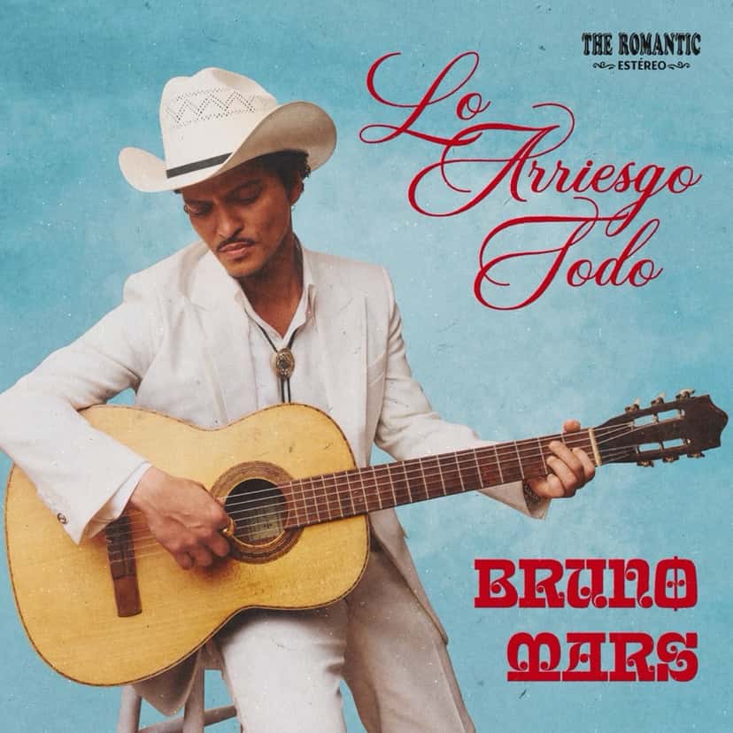 Portada del single «Lo Arriesgo Todo», de Bruno Mars: el cantante, de traje blanco y sombrero vaquero, toca una guitarra criolla sobre un fondo celeste
