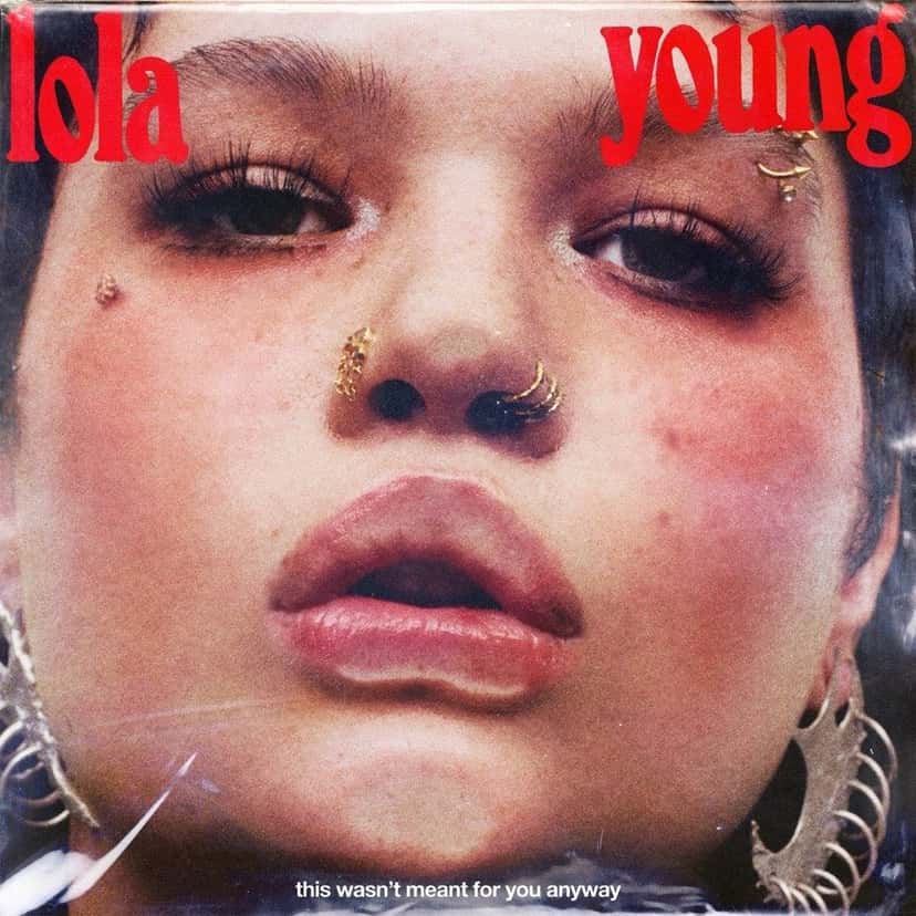Portada de «This Wasn't Meant For You Anyway», de Lola Young: primer plano del rostro de la cantante, con piercings en la cara, y su nombre en letras rojas