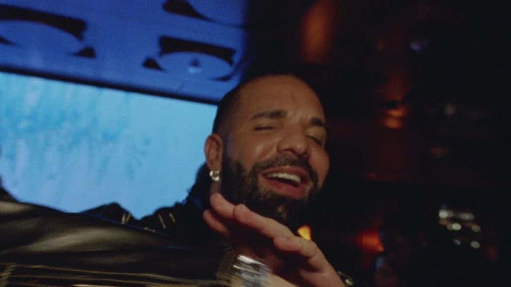 Drake sonríe con los ojos cerrados en un salón con luces azules, en el video oficial de «Solar Eclipse», con Don Toliver (fotograma del video oficial, foto de archivo)