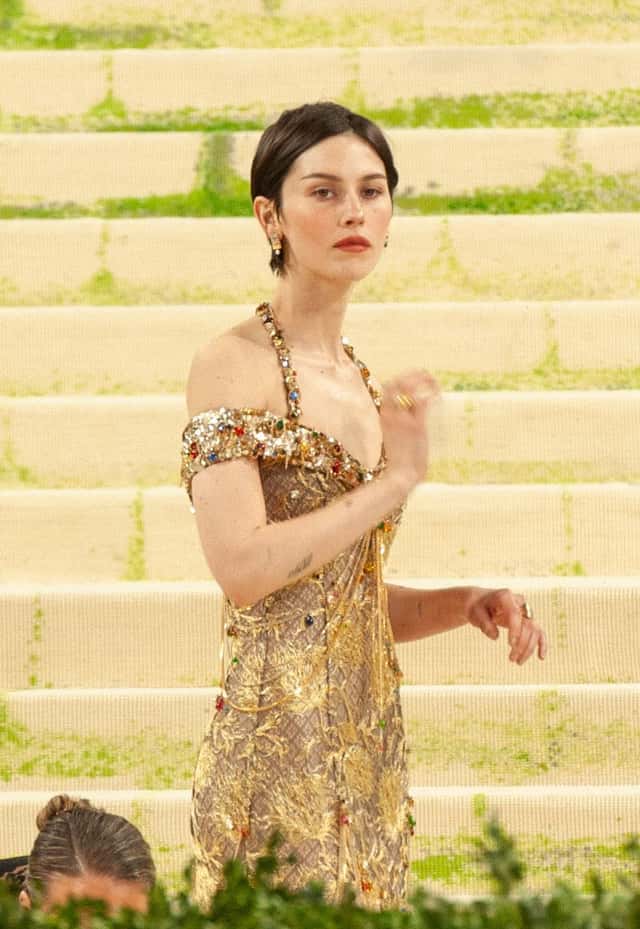 Gracie Abrams en la gala del Met de mayo de 2026, con el pelo corto y un vestido dorado con bordados y pedrería, en la escalinata del museo (foto de archivo). Foto: SWinxy, CC BY 4.0, vía Wikimedia Commons