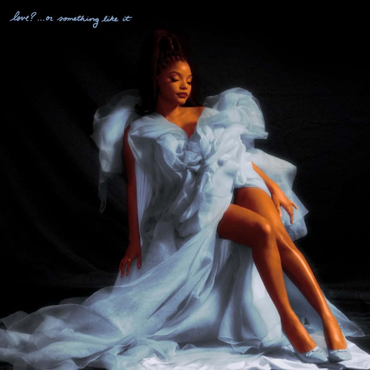 Portada de la edición deluxe de «love?... or something like it»: Halle Bailey, sentada, con un vestido blanco de volados vaporosos sobre fondo negro