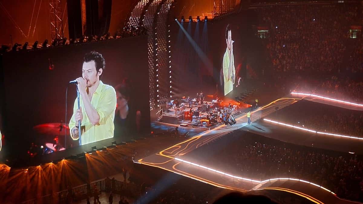 Harry Styles canta en el escenario de su gira Together, Together en Ámsterdam, con su imagen en las pantallas gigantes y luces naranjas (foto de archivo, mayo de 2026)