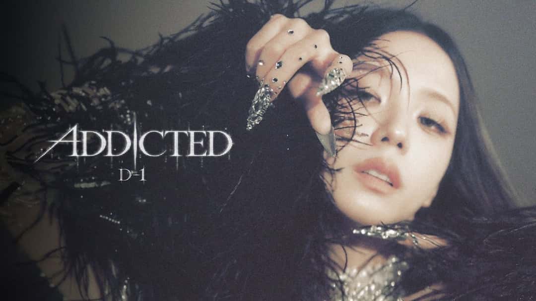 Primer plano de Jisoo con plumas negras, uñas largas con piedras brillantes y la mano sobre la cara, junto al título «ADDICTED» y la leyenda «D-1», en la imagen oficial del día anterior al lanzamiento