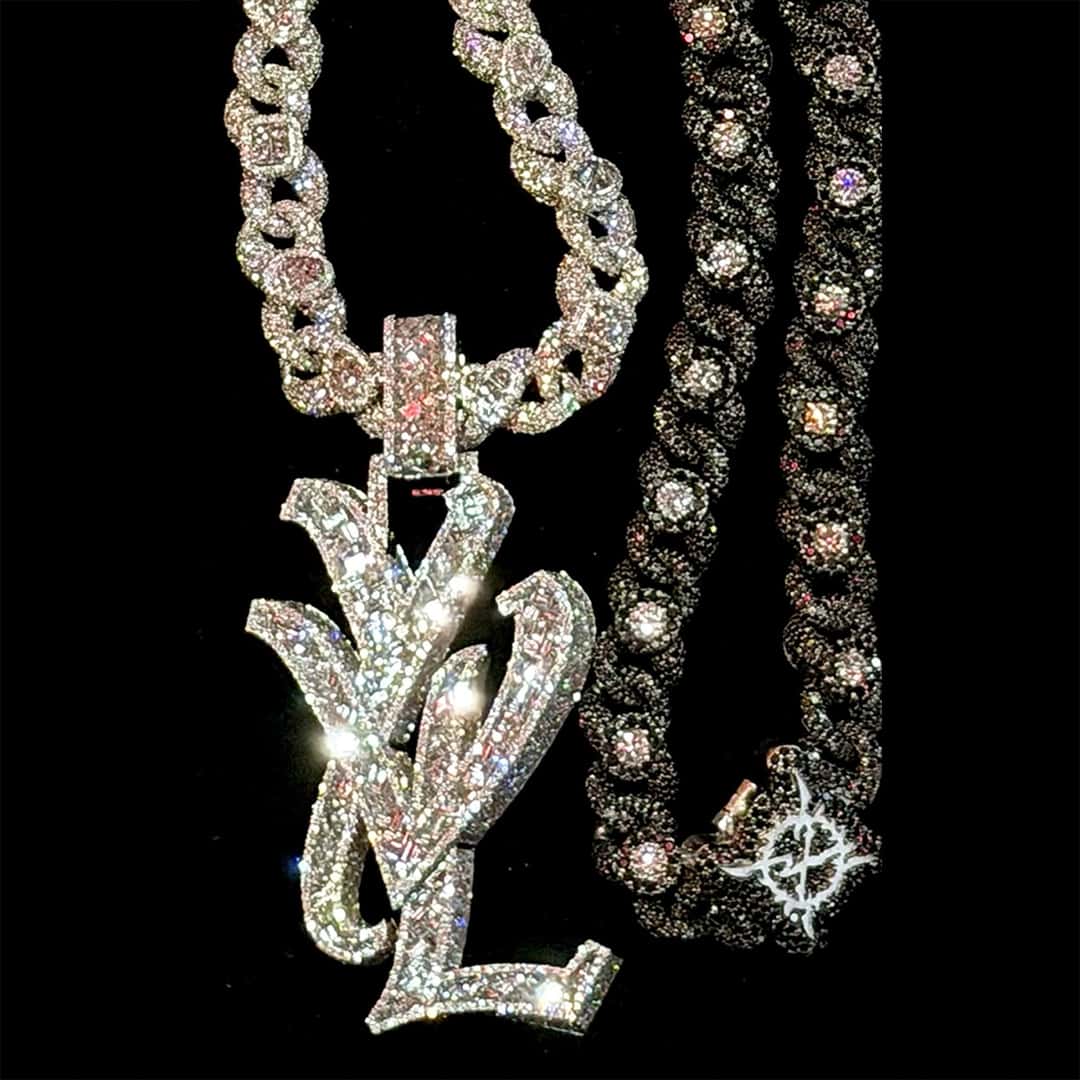 Portada de «the acronym», el single de Ken Carson con Destroy Lonely: dos cadenas con brillantes, una con un dije de letras plateadas, sobre fondo negro