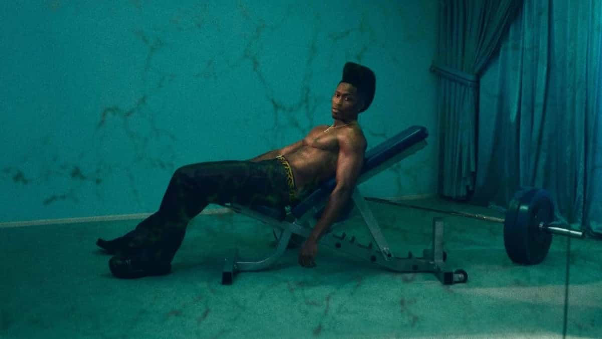 Imagen oficial de «ALOUD!» de Lucky Daye: el cantante sin remera, recostado en un banco de pesas en un salón turquesa con cortinas y paredes de mármol