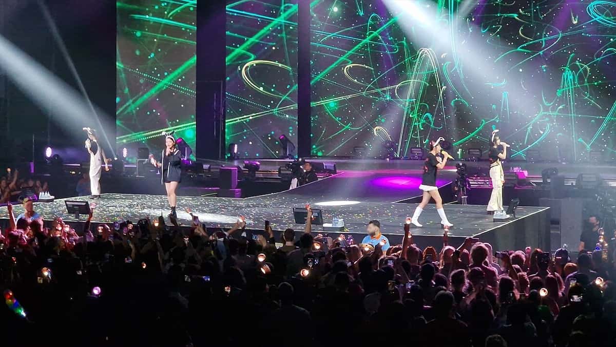 Red Velvet en el escenario de su show de Ámsterdam en mayo de 2023, con pantallas verdes y luces blancas sobre el público (foto de archivo)