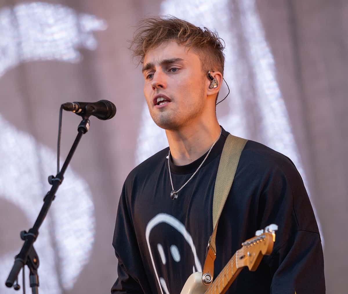 Sam Fender canta con la guitarra colgada, de remera negra con una carita sonriente, en el festival Boardmasters de 2021 (foto de archivo)