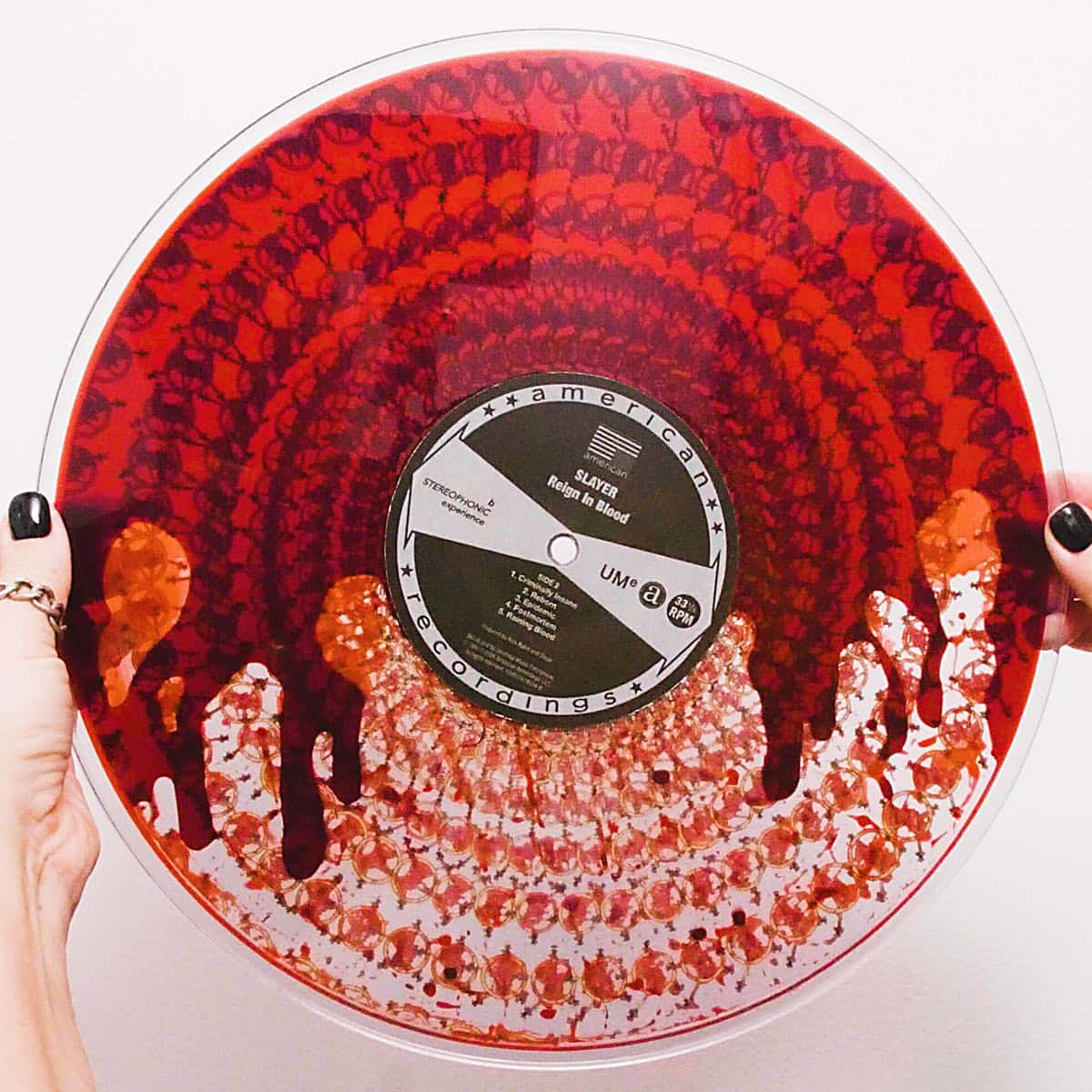Foto oficial del vinilo zoetrope de "Reign in Blood" de Slayer por los 40 años: un disco transparente lleno de líquido rojo, sostenido con las dos manos, con la etiqueta de American Recordings en el centro