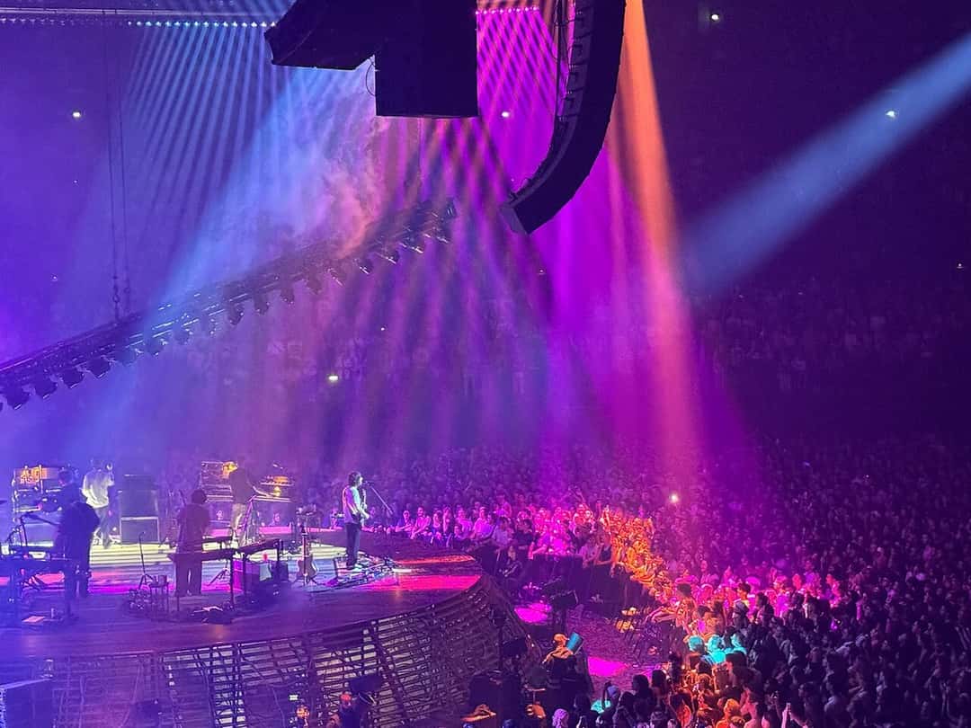 Tame Impala en vivo en un estadio cubierto de Lyon, con luces violetas y rosas sobre el público, durante el Deadbeat Tour en abril de 2026 (foto de archivo)