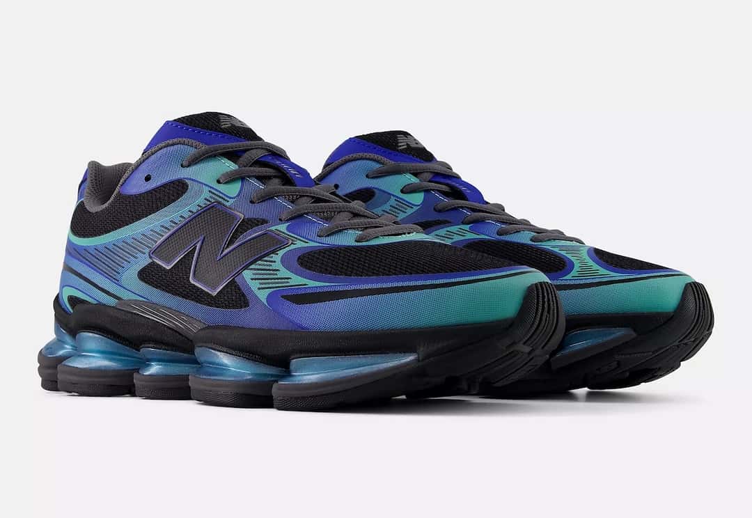 New Balance 2000 Metallic Pack azul de perfil, con malla negra, la N grande y las líneas verde agua y azul, sobre fondo claro