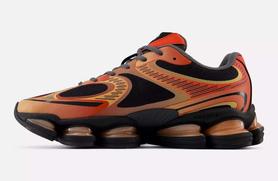 New Balance 2000 Metallic Pack naranja de perfil, con malla negra y gráficos de llamas en rojo, naranja y amarillo, sobre fondo claro