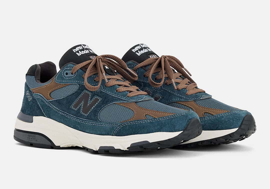 Par de New Balance 993 Made in USA Shadow Blue en vista tres cuartos, con cordones marrones, lengüeta negra con el texto Made in USA y entresuela blanca
