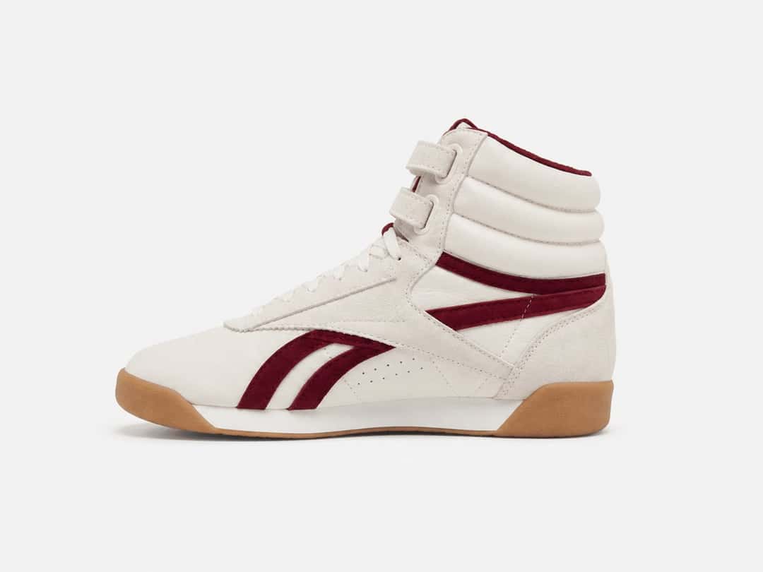 Reebok Freestyle Hi de Rouje en cuero crema con las rayas de Reebok en bordó, dos tiras con abrojo en el tobillo y suela de goma marrón