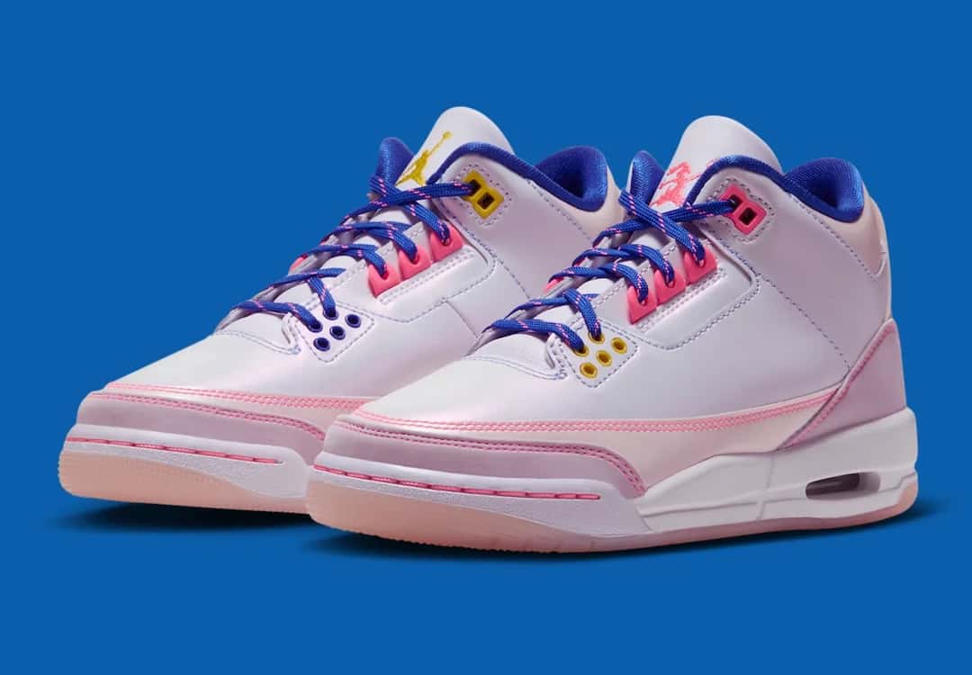 Par del Air Jordan 3 SE Lola Bunny para chicas sobre fondo azul, con upper blanco perlado, overlays rosa claro, costuras y ojales rosa fuerte, cordones azules con motas rosas, interior azul y logos de Jumpman amarillo y de Lola en rosa en las lengüetas