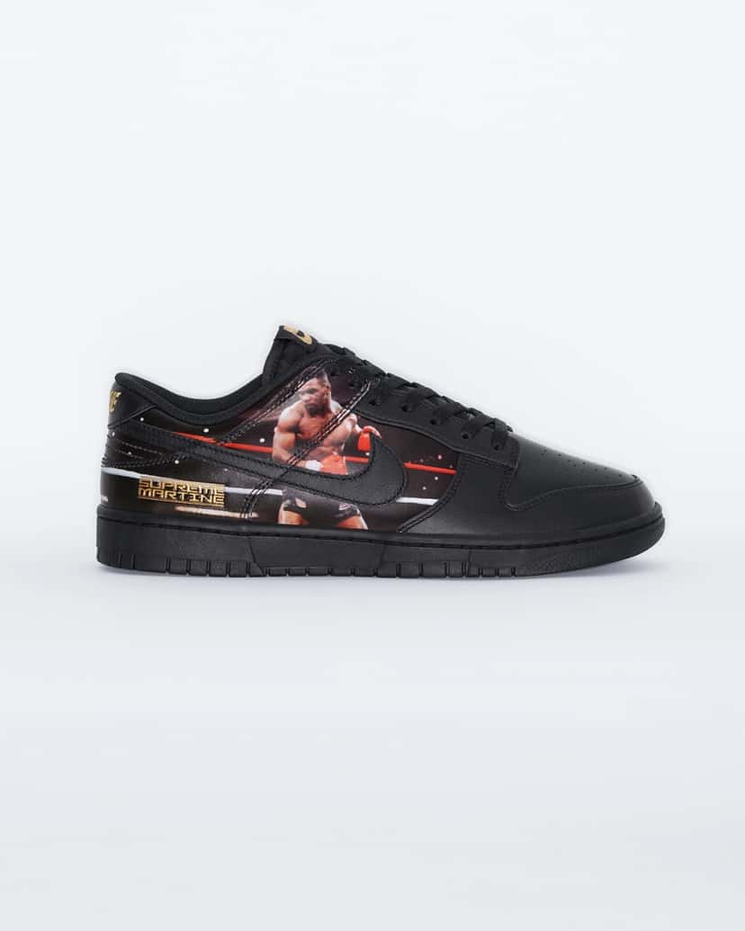 Vista lateral del Supreme x Martine Rose x Nike Dunk Low Tyson sobre fondo blanco, en cuero negro con suela negra, la foto de Mike Tyson con guantes rojos en el ring detrás del swoosh negro y la placa dorada Supreme Martine cerca del talón