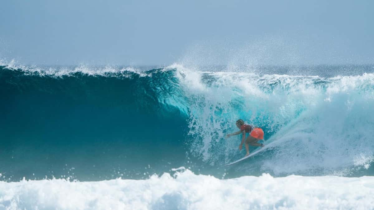 Caitlin Simmers, con lycra roja y short naranja, adentro de un tubo de agua turquesa en Cloud 9, Siargao, en el primer día del Philippines Pro