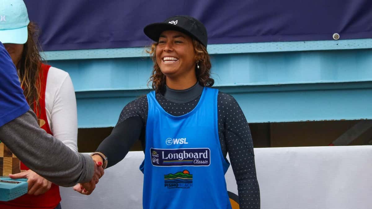 Lia Diaz sonríe y da la mano, con la lycra celeste del Surfing For Hope Longboard Classic, en la premiación de Pismo Beach en 2025 (foto de archivo)