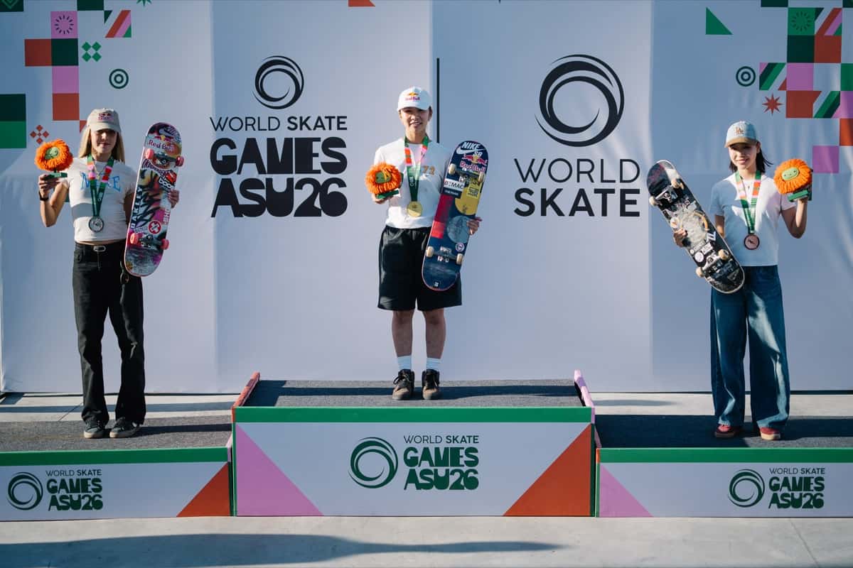 Podio femenino del Mundial de street en Luque: Yumeka Oda, con gorra y remera blancas y short negro, en el escalón más alto con su medalla de oro, entre Chloe Covell, a la izquierda, y Coco Yoshizawa, a la derecha, todas con flores naranjas y sus tablas en la mano