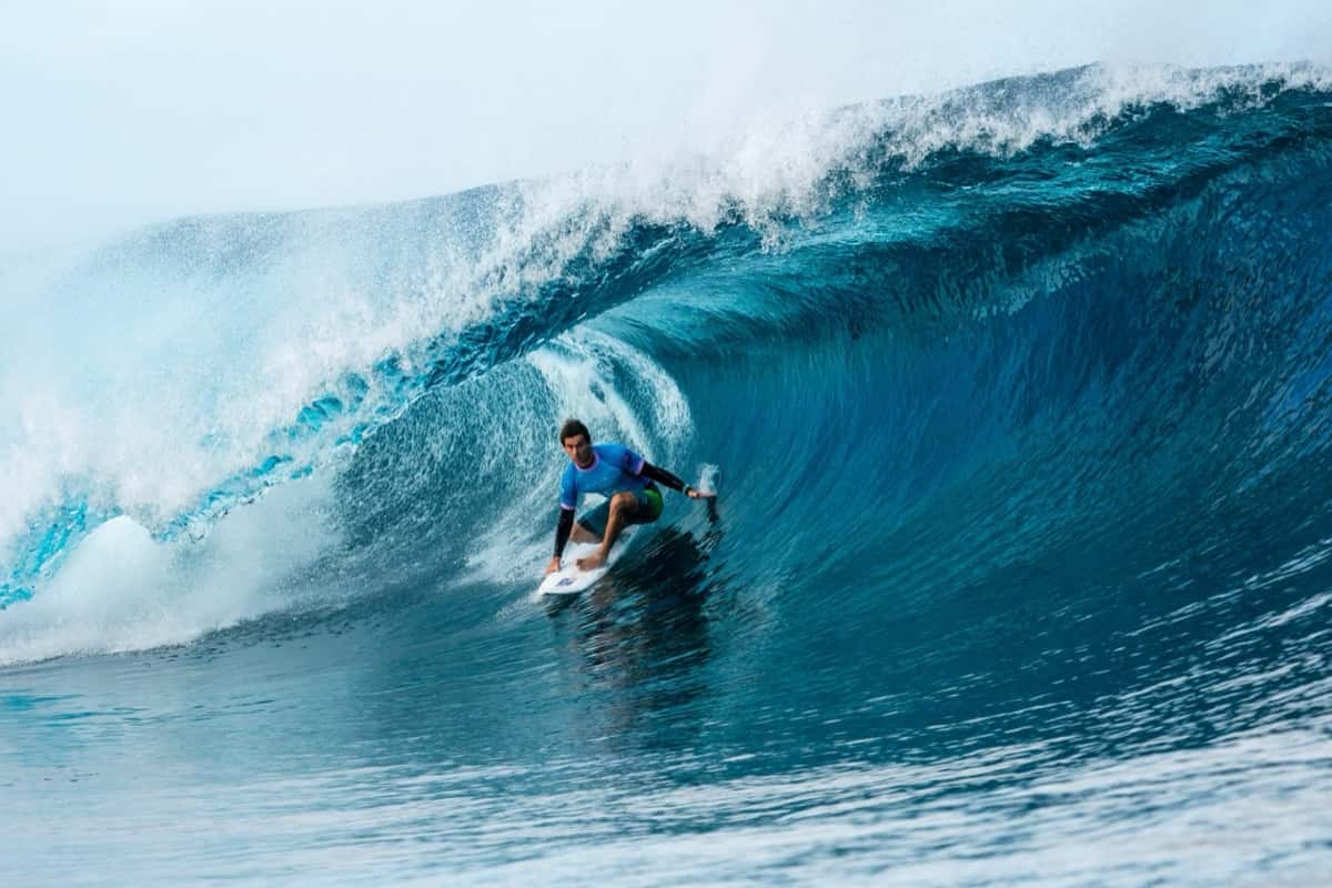 Jack Robinson agachado dentro del tubo de una ola azul en Teahupo'o durante los Juegos de París 2024 (foto de archivo)