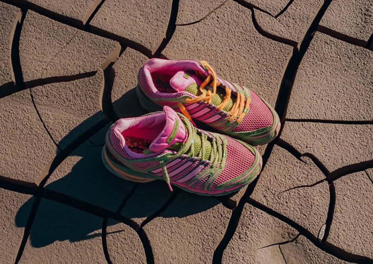 Par de The Tipping Point x adidas Adistar Control 5 rosa y verde apoyado sobre tierra seca y agrietada