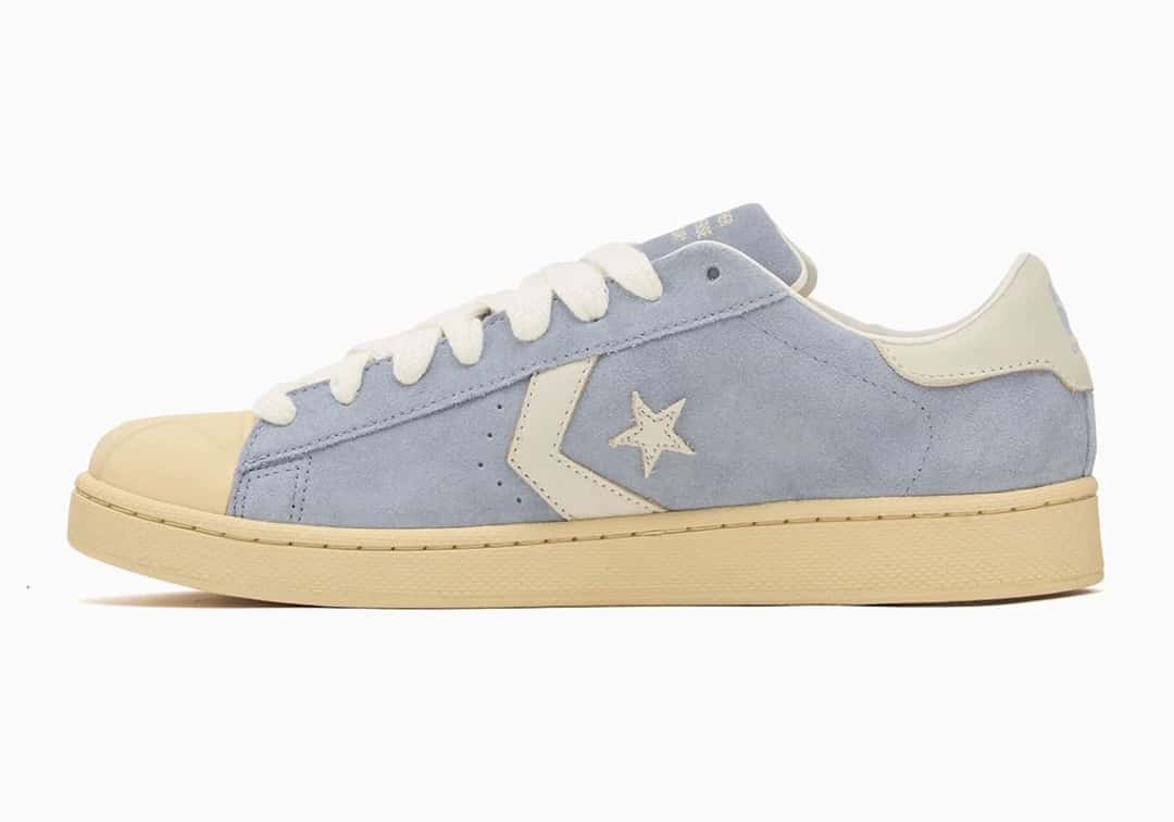 Converse Pro Leather de GOLF le FLEUR* en azul lavanda de perfil sobre fondo blanco, con upper de gamuza azul, estrella y chevron crudos, talón crudo, puntera moldeada y suela color crema