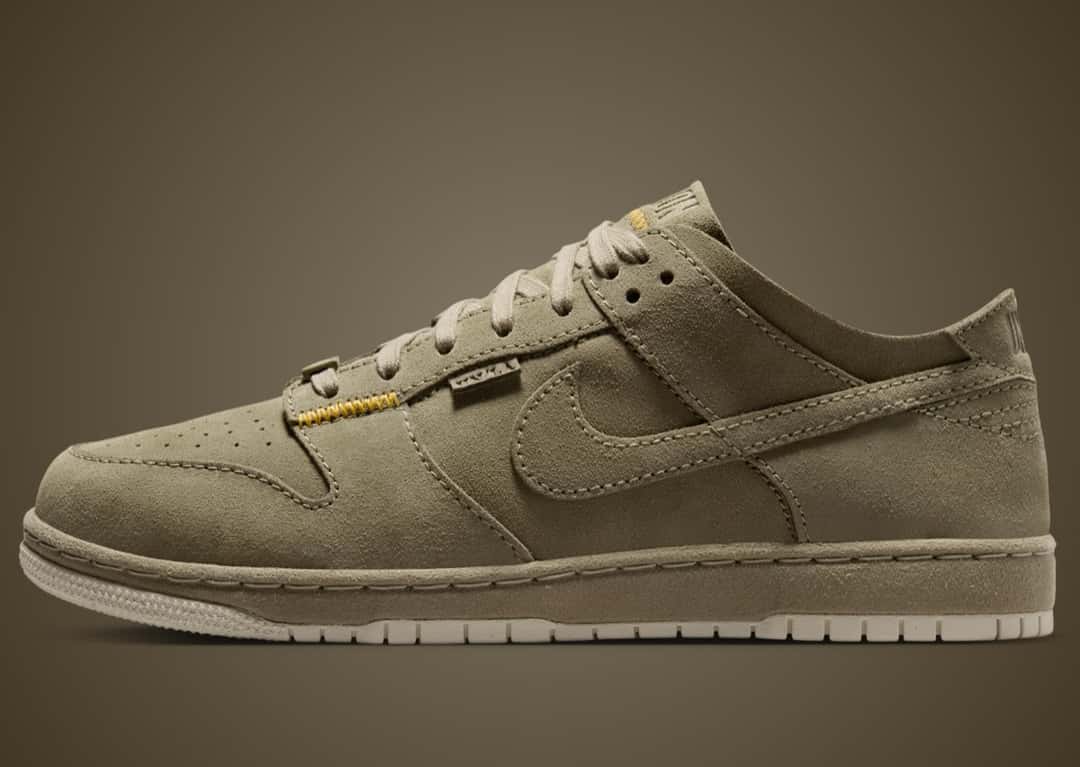 Union x Nike Dunk Low Natural Selection Fatigue en gamuza verde oliva, de perfil, con la etiqueta de Union en el lateral