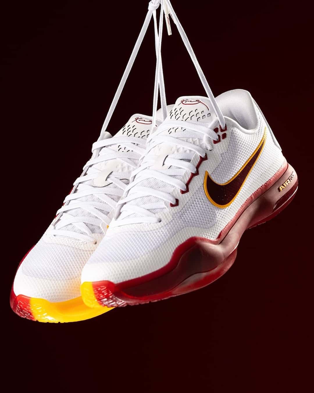 Nike Kobe 10 Protro blanca de USC colgada de los cordones, con Swoosh bordó y media suela amarilla y bordó