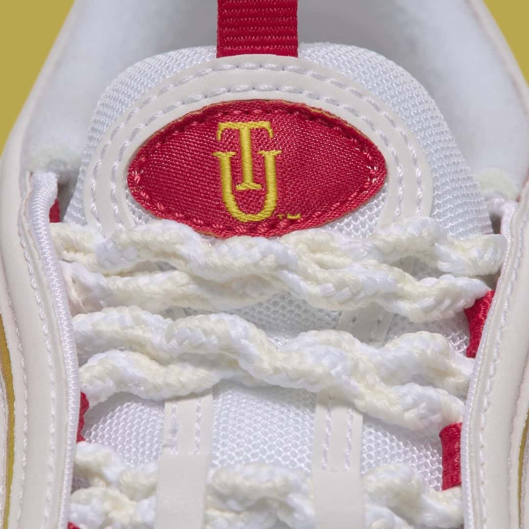 Lengüeta de la Nike Air Max 97 Yardrunners de Tuskegee, con las iniciales TU bordadas en dorado sobre un óvalo rojo y cordones trenzados blancos